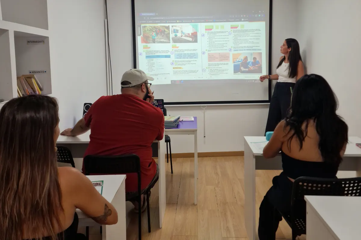 Clase de adultos en grupo reducido con la profesora junto al proyector