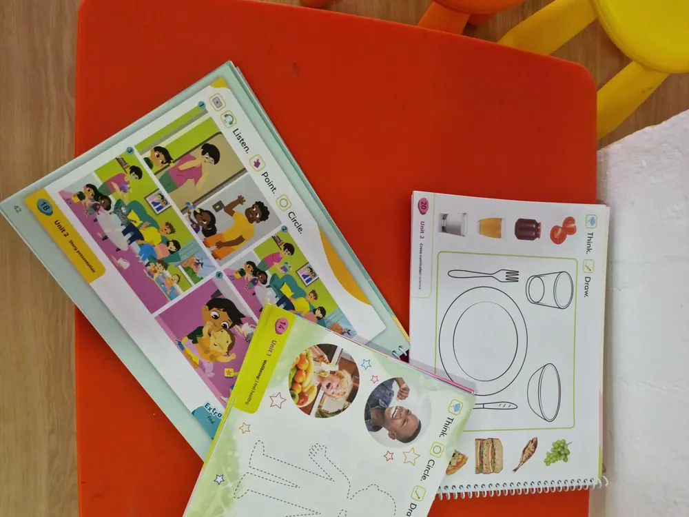 Cuadernos de actividades infantiles sobre una mesa roja