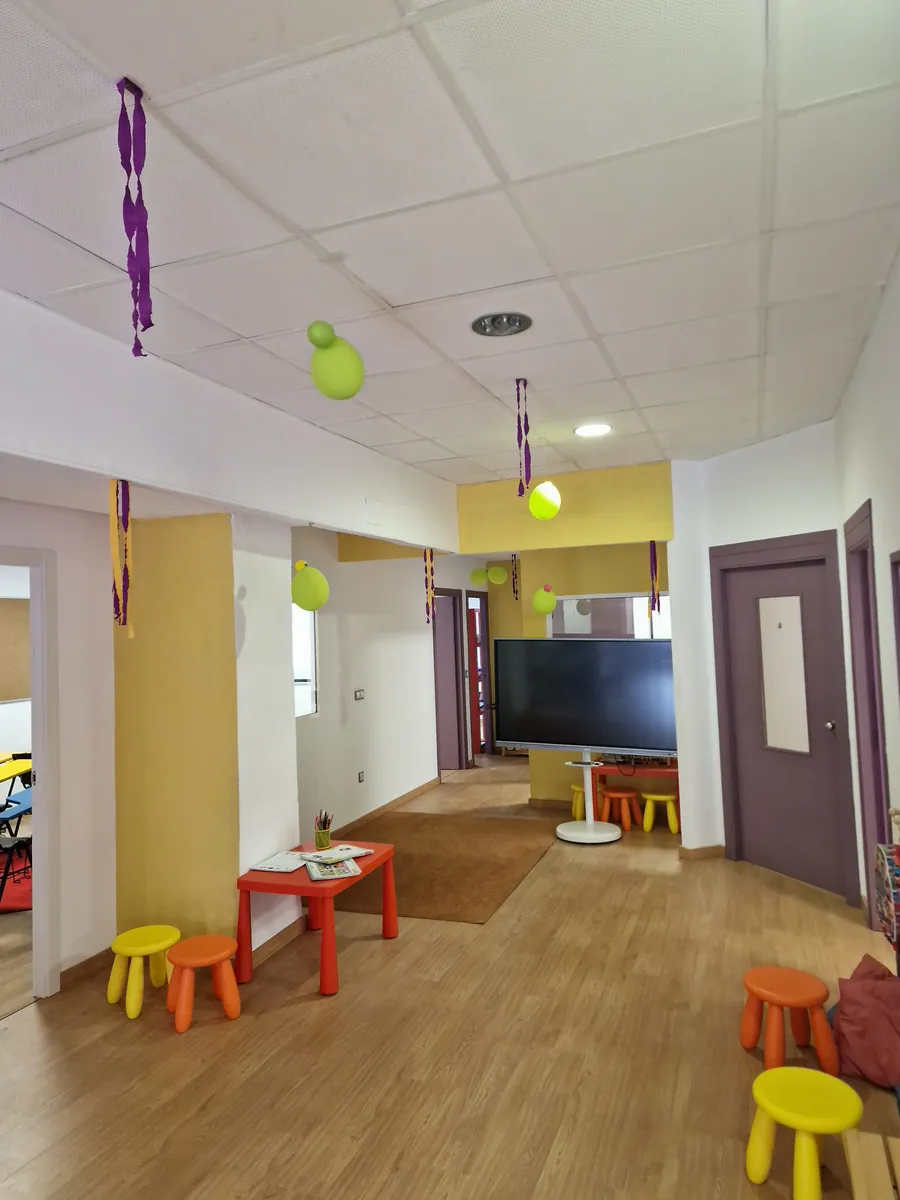 Zona de entrada de la academia, con mesas y taburetes de colores